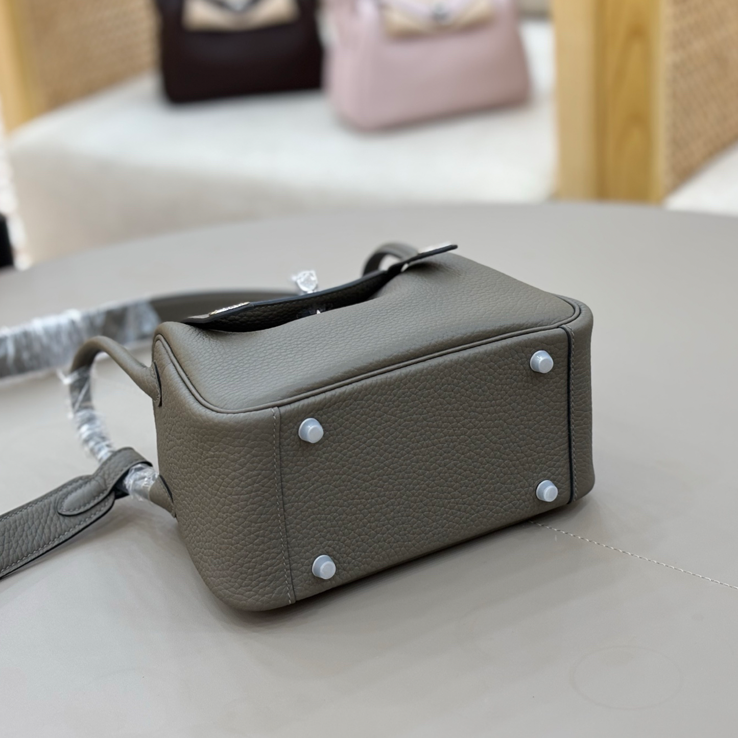 Muted Graphite Grey Pebbled Grain Compact Curved Saddle Shoulder Bag With Silvery Turn Lock Hardware, Dual Side Zip Closures And Base Defensive Round Studs