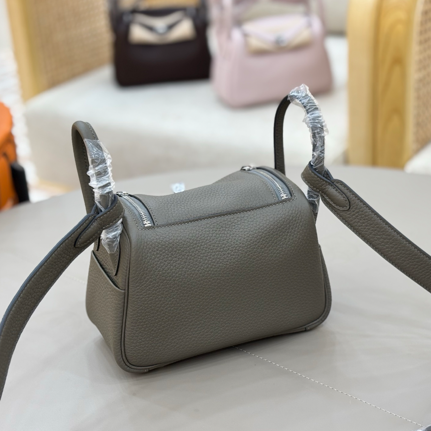 Muted Graphite Grey Pebbled Grain Compact Curved Saddle Shoulder Bag With Silvery Turn Lock Hardware, Dual Side Zip Closures And Base Defensive Round Studs