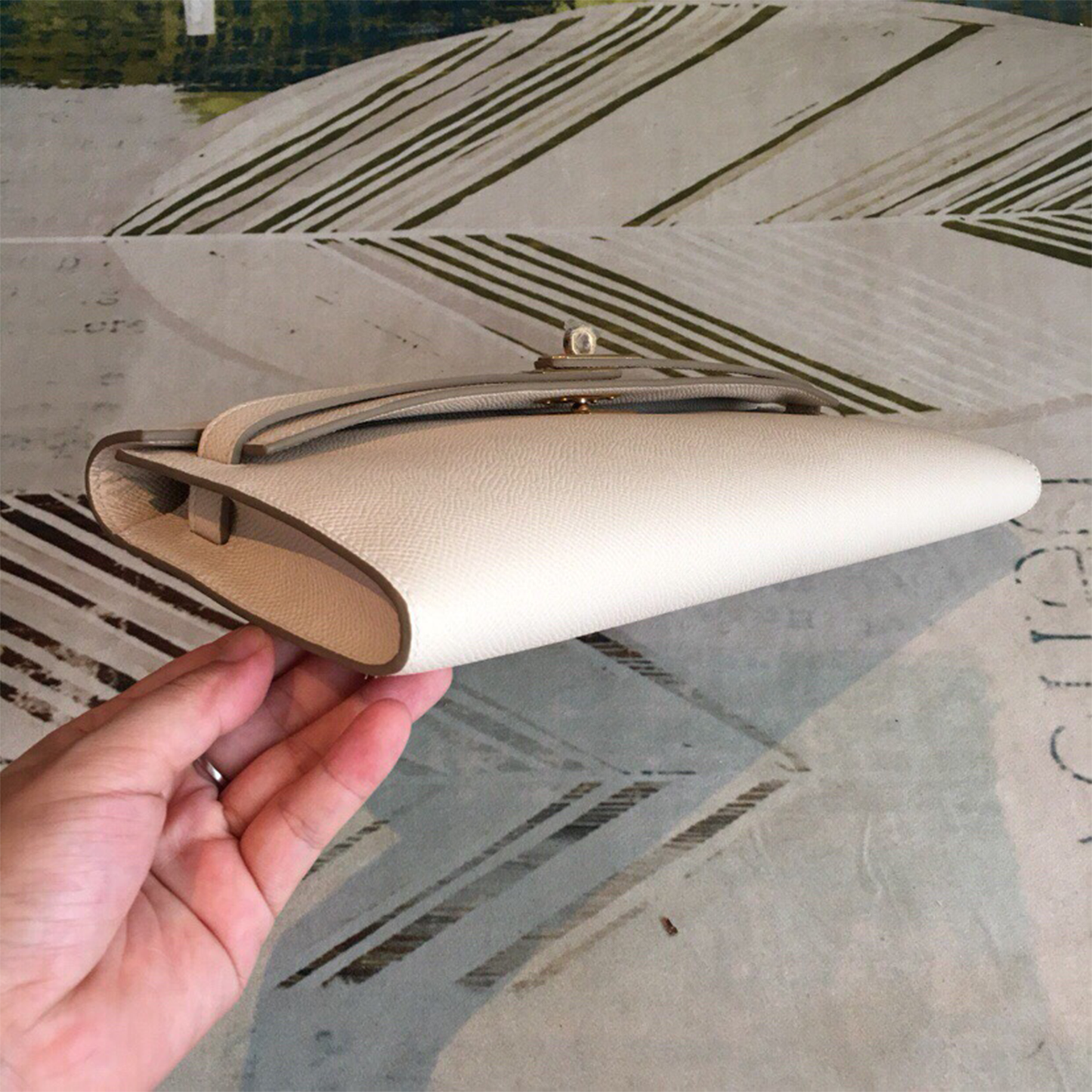 Soft Creamy Off-White Crosshatch Grain Slim Elongated Hand Clutch With Taupe Trim, Polished Golden Twist Lock Hardware And Curved Mini Top Carry Grip